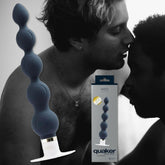 A grayscale image of two people embracing closely, with a colored product image overlaid. The product is the VeDO 'Quaker,' a blue, beaded intimate item made of smooth silicone texture from VeDO, featuring various vibration modes, placed beside its packaging.